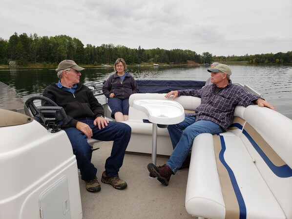 Three people on a boat with a steering wheel and a small table.