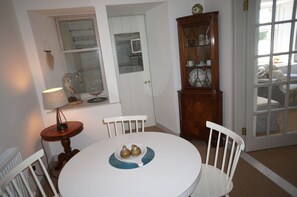 Un coin repas comprenant une table ronde, deux chaises, une lampe et un buffet en bois doté de portes en verre.