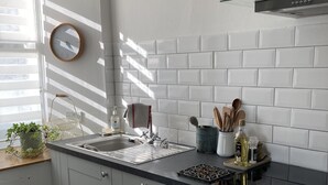 Une cuisine moderne avec des armoires blanches, un comptoir noir et une hotte de cuisinière en acier inoxydable.