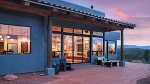 A modern house with large windows, outdoor seating, and a view of the hills. - Walls of Glass - Panoramic Views, Hot Tub, Fire Pit Under the Stars (Sedona)