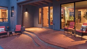 A modern building with a patio area featuring wicker chairs and a brick pathway. - Walls of Glass - Panoramic Views, Hot Tub, Fire Pit Under the Stars (Sedona)
