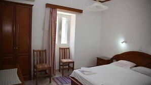 A bedroom with a bed, a chair, a wardrobe, and a window with curtains.