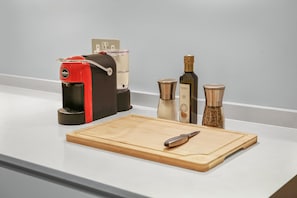 A kitchen counter with a coffee machine, a cutting board, a knife, and two spice containers.