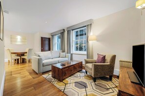 Una sala de estar moderna con un sofá, un sillón, una mesa de centro y un televisor.