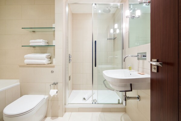 A modern bathroom with a glass shower enclosure, a white sink, and a toilet.