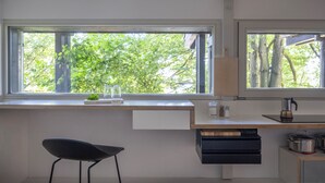 A modern kitchen with a large window, a built-in desk, and a chair. - Modern Minimalistic Seeblick Design Studio mit Küche, Terrace und Parkplatz (Sipplingen)