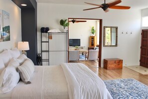 Ein Schlafzimmer mit Bett, Deckenventilator, Fernseher, Schreibtisch und Stuhl.