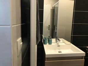 Moderni kylpyhuone, jossa on suuri pesuallas, peili sekä mustavalkoiset laatat.