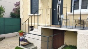 A two-story house with a balcony, a small garden, and a wooden door.