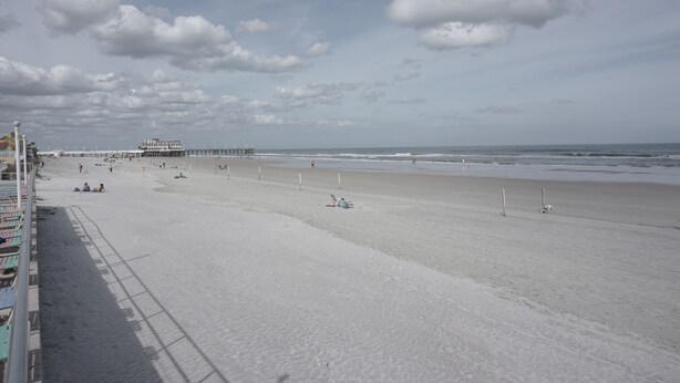 A wide beach with a pier in the distance. - Oceanfront Building Studio Queen Bed Smart TV Pool (Daytona Beach)