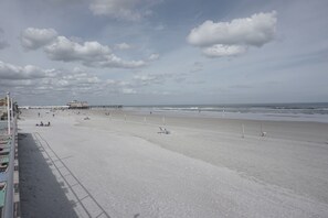 A wide beach with a pier in the distance.