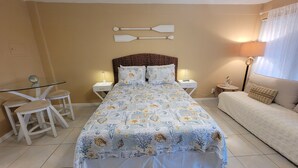 A bedroom with a bed, a nightstand, a lamp, a chair, and a sofa. - Oceanfront Building Studio Queen Bed Smart TV Pool (Daytona Beach)