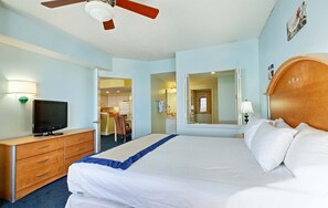 Habitación de hotel con cama, televisión, escritorio y baño visible a través de una puerta abierta.