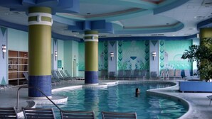 A large indoor swimming pool with multiple lanes, lounge chairs, and a mural on the walls.