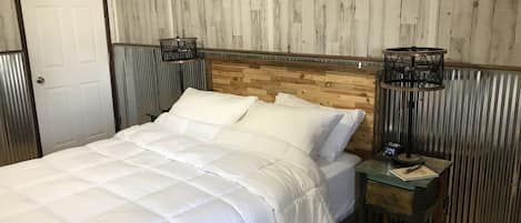 A bed with a wooden headboard, white bedding, and two bedside tables with lamps.