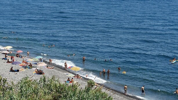 A beach with people swimming and sunbathing, umbrellas, and a clear blue sky. - Lemon's house by the sea (Sicilia)