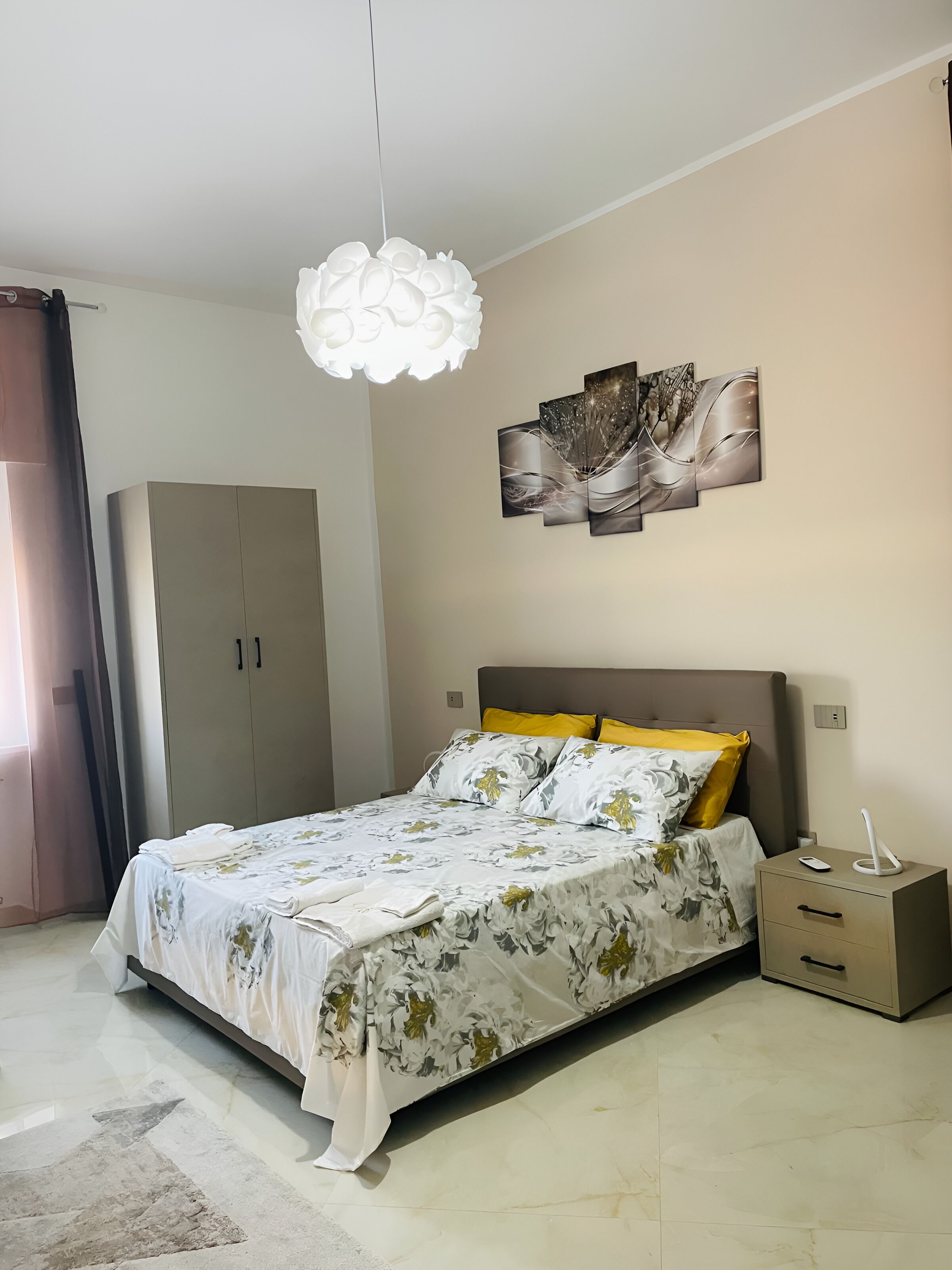 Une chambre à coucher comprenant un lit, une armoire, une table de chevet et une œuvre d’art accrochée au mur.