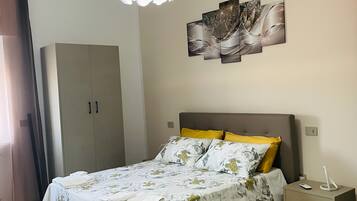 Une chambre à coucher comprenant un lit, une armoire, une table de chevet et une œuvre d’art accrochée au mur.