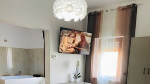 A modern bedroom with a bed, desk, and a large TV.