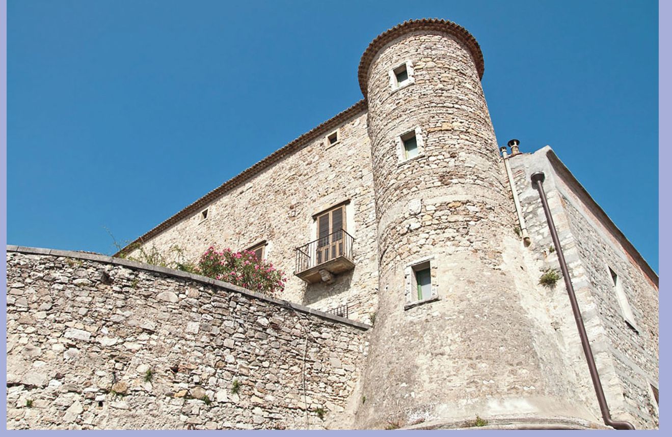 Un bâtiment en pierre doté d’une tour et d’un balcon.