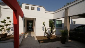 Une maison moderne avec une arche rouge, un garage et des plantes en pot.