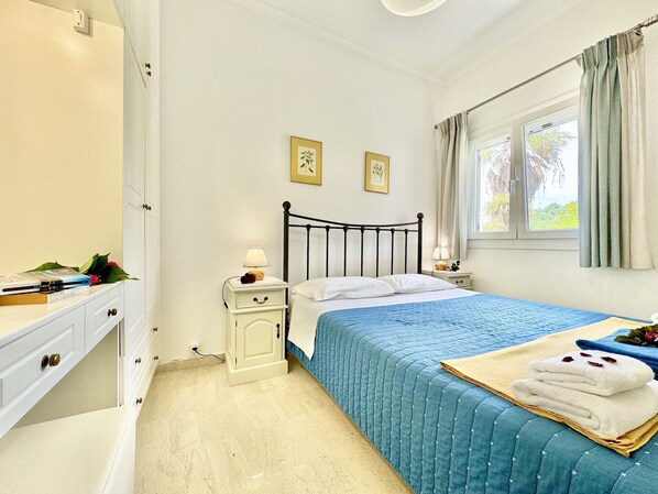 A bedroom with a bed, bedside tables, a dresser, and a window with curtains.