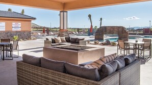 Ein Außenbereich mit Lounge-Möbeln, Feuerstelle und Pool.