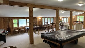 A spacious indoor area with a pool table, multiple tables and chairs, and large windows providing natural light. - Quiet resort condo close to Goose Rocks beach (Kennebunkport)
