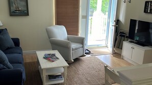 A living room with a sofa, armchair, coffee table, and a TV stand. - Quiet resort condo close to Goose Rocks beach (Kennebunkport)