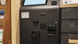 A self-service kiosk with a screen displaying information, a card reader, and a cash dispenser.