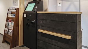 A reception area with a black reception desk, a wooden counter, a digital kiosk, and a wall-mounted information board.