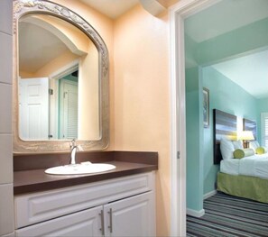 Classic design with a large mirror, white vanity, and striped carpet.