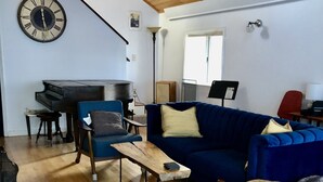 A living room with a blue sofa, wooden coffee table, and a grand piano.