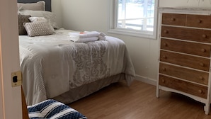 Un dormitorio con cama, cómoda, ventana y espejo.