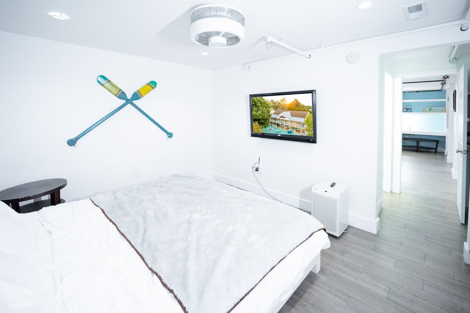 Ein modernes Hotelzimmer mit einem großen Bett, einem an der Wand montierten Fernseher und Blick auf den Poolbereich.