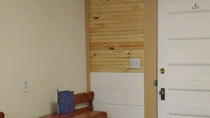 Ein Holzespeisetisch mit Stühlen, ein gemustertes Teppich und eine weiße Tür mit kleinem Fenster.