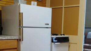 Eine kleine Küche mit Kühlschrank, Herd und Holzschränken.