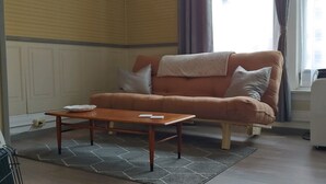 Ein Wohnzimmer mit braunem Sofa, einem Holztisch und einer weißen Klimaanlage.