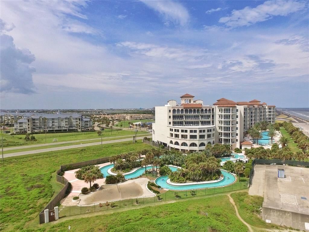 Un hotel con zona de piscina, varias construcciones y vista a la playa.