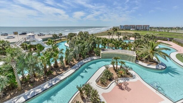 Ein Resort mit großem Swimmingpool, Palmen und Blick auf den Strand.