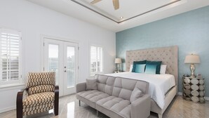 A bedroom with a bed, two nightstands, a ceiling fan, and a sofa.
