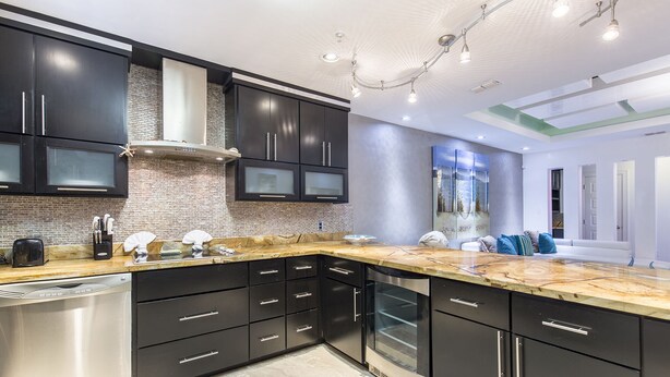 A modern kitchen with dark cabinetry, a marble countertop, and a dishwasher.