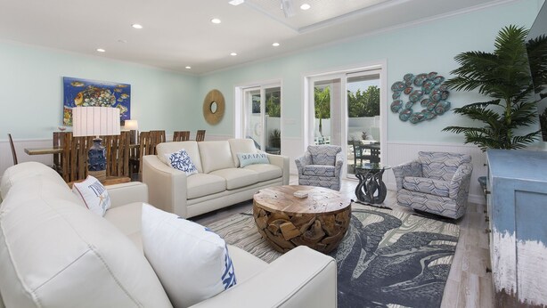 A spacious living room with a white sofa, a patterned armchair, and a round wooden coffee table. - Luxury Coastal Retreat​​​​​​​ • Heated Pool & Hot Tub • 3 Min Walk to Beach (South Padre Island)