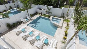 A pool area with multiple lounge chairs and a hot tub. - Luxury Coastal Retreat​​​​​​​ • Heated Pool & Hot Tub • 3 Min Walk to Beach (South Padre Island)