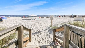 A wooden boardwalk leading to a sandy beach with umbrellas and beach chairs. - Totally Beachin - Condo with Stunning Ocean Views (Orange Beach)