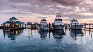 A marina with several boats docked at wooden piers, a small building with a green roof, and a cloudy sky. - Totally Beachin - Condo with Stunning Ocean Views (Orange Beach)