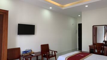 A hotel room with two beds, a desk with a chair, a TV mounted on the wall, and a mirror.