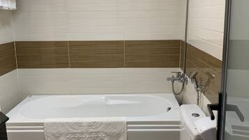 Een badkamer met een bad, toilet en douche.
