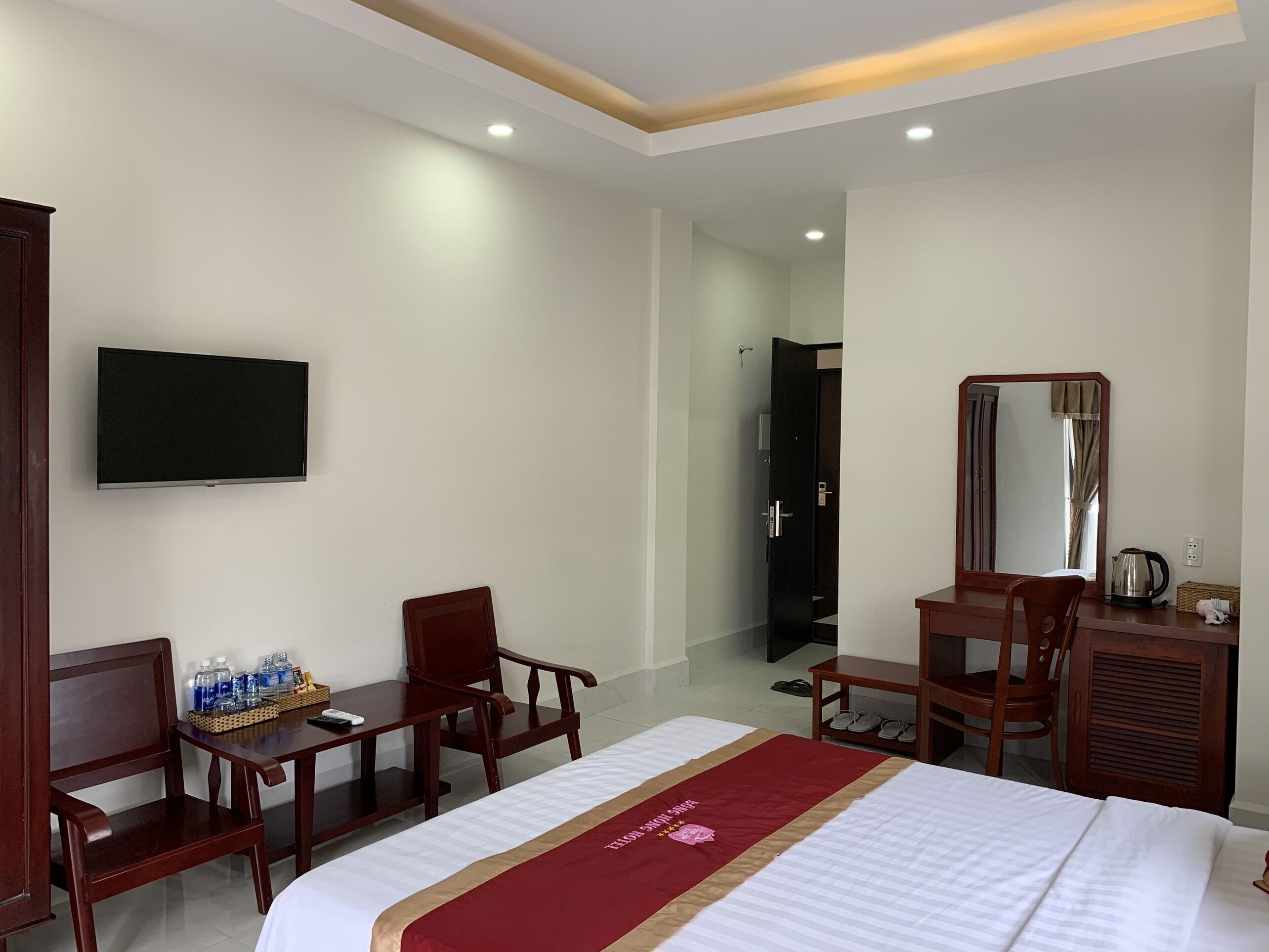 Une chambre d’hôtel comprenant un lit, un bureau avec une chaise, une télévision, une armoire et un miroir.
