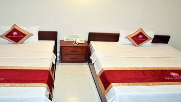 Two twin beds with matching headboards and footboards, a bedside table with a phone, and a wall-mounted light fixture.